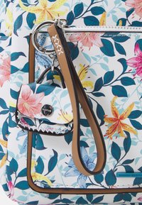Sac à motif floral avec une base blanche, présentant des fleurs roses et jaunes. Comprend une petite poche accessoires amovible avec une poignée.