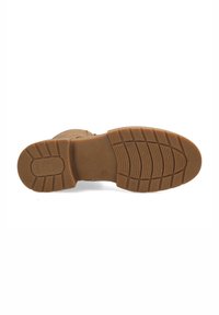 Suela de bota de goma marrón con un patrón texturizado, que presenta surcos y líneas elevadas para mayor tracción. Texto motivacional estampado en la superficie.