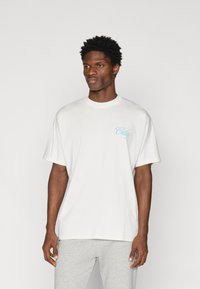 Camiseta de algodón blanca con cuello redondo y mangas cortas, que presenta un texto impreso en azul claro "City" en el lado izquierdo del pecho.