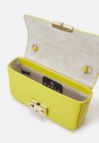 Borsa a tracolla gialla in pelle con finitura testurizzata, chiusura in metallo dorato e interno foderato in suede beige. Presenta un’etichetta del marchio all'interno.