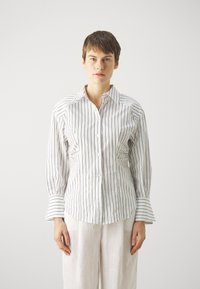 Hvit skjorte med lange ermer og knapper, vertikale mørke striper, strukturert passform og utvidede mansjetter. Glatt bomullsstoff med skreddersydd design.