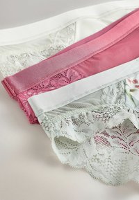 Trois pairs de culottes à bordure de dentelle en blanc, rose et vert clair. Les matériaux doux présentent des motifs de dentelle florale et géométrique sur les bords.