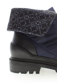 Stivale blu navy con parte superiore nera impermeabile, dotato di un gambale pieghevole con motivo e suola in gomma testurizzata. Logo del marchio visibile.