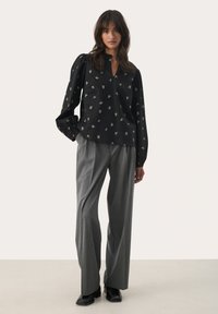 Black long-sleeve blouse with gold floral pattern, V-neck, and puffed sleeves; paired with gray pinstriped wide-leg trousers and black boots.