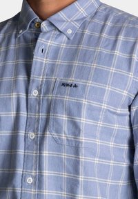 Lichtblauw geruit overhemd van stof met een zachte textuur. Bevat een button-down kraag, witte knopen en een borstzak met borduursel.