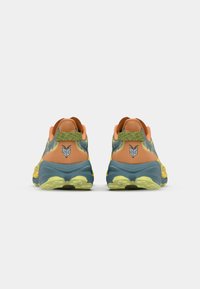 Zapatillas deportivas con una combinación de colores naranja y azul, tela texturizada, un talón con patrón y una suela amarilla de alta tracción.