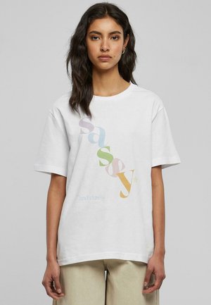 T-shirt en coton blanc avec une coupe décontractée. Présente un texte multicolore affichant "sassy" et "and classy", présenté dans des polices et tailles variées.
