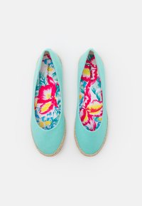Sapatilhas de tela azul clara com sola de juta. O interior apresenta um padrão floral colorido em rosa, amarelo e azul. Design clássico e arredondado.