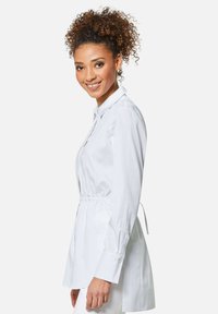 Weißes Langarmshirt mit knöpfbaren Manschetten, elastischem Bund und lockerer Passform. Verfügt über einen Kragen und eine glatte Baumwolltextur.