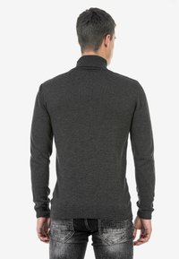 Dunkelgrauer Pullover mit langen Ärmeln und hohem Kragen, aus weichem Strickmaterial. Mit gerippten Bündchen und Saum, in taillierter Passform.