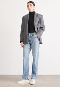Grå ullblanding blazer over en svart turtleneck, sammen med lyseblå ripped jeans og hvite sneakers. Enkelt design med en avslappet passform.