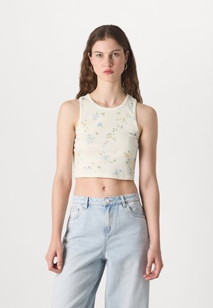 Top court à rayures florales en crème clair avec des fleurs bleues et jaunes. Associé à un jean en denim bleu clair taille haute.