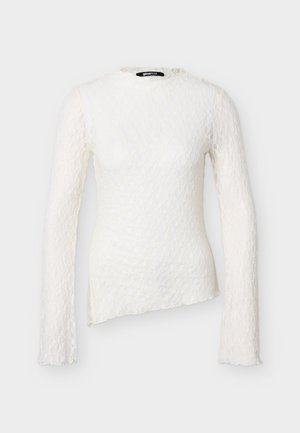 Λευκό δαντελένιο τοπ με μακριά μανίκια, ψηλό λαιμό και ασύμμετρο τελείωμα, με λεπτό floral δαντελένιο μοτίβο και εφαρμοστή σιλουέτα.