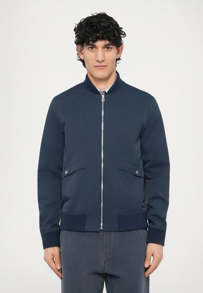Giubbotto bomber blu navy con zip frontale, polsini a costine e due tasche laterali. Tessuto liscio con vestibilità sartoriale e design minimalista.