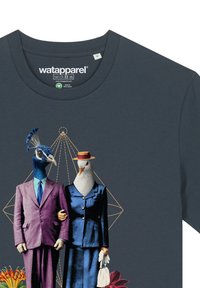 Dunkelgraues T-Shirt mit einem Pfau in einem lila Anzug und einer Möwe in einem blauen Anzug mit Hut, vor geometrischen Designs und floralen Details.
