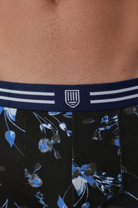 Mehe alumine kehaosa habemenuga sarnase karvkattega, mustade bokserpükstega, millel on sinine lillemuster ja tumesinine vöökoht valgete triipude ja logoga.