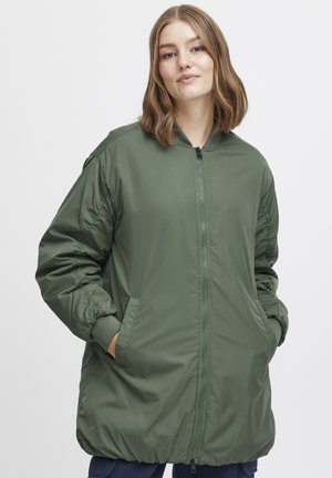 Veste bomber verte rembourrée avec fermeture éclair à l'avant, poignets élastiques et poches latérales ; elle possède une texture extérieure lisse et une coupe ample.
