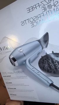 Hårtork med metallblå kropp och munstycksmunstycke. Kontrollknappar finns på handtaget, tillsammans med en texturerad svart diffuser i närheten.