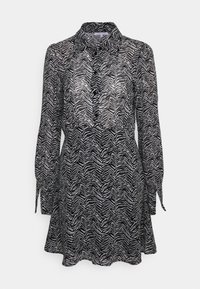 Robe à imprimé zèbre noir et blanc, en matériau léger et transparent, avec des manches longues, un col, un bouton sur le devant et des accents à nouer.