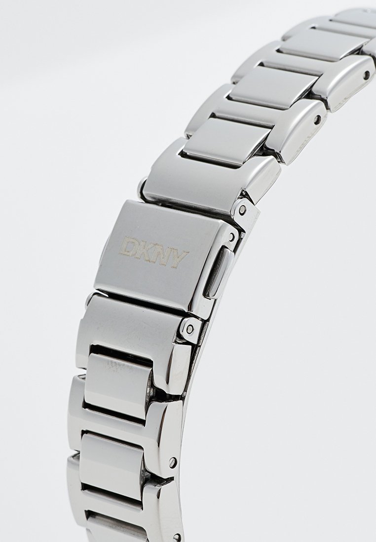 Silberner Edelstahl-Armbanduhr mit Gliederarmband-Design, versehen mit dem eingravierten DKNY-Logo auf einem flachen, rechteckigen Verschluss. Glatte, polierte Oberfläche.