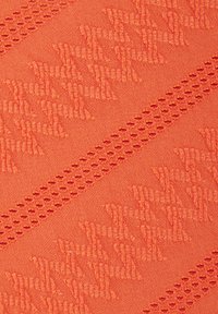 Textúrovaná oranžová tkanina s vyvýšenými vzormi a malými perforovanými detailmi, vytvárajúca hmatový povrch. Hladký povrch.