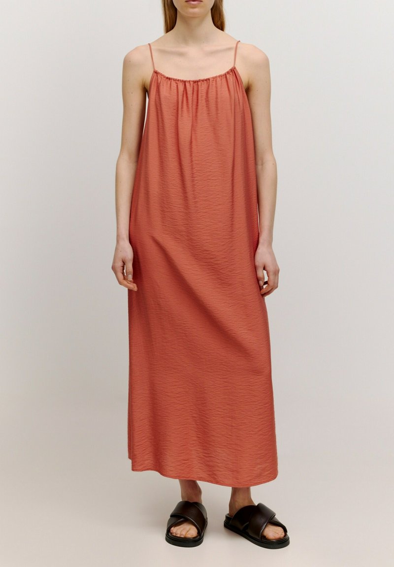Maxikleid in gedämpftem Koralle, aus leichtem Stoff mit strukturierter Oberfläche. Verfügt über dünne Träger und eine lockere, fließende Silhouette.
