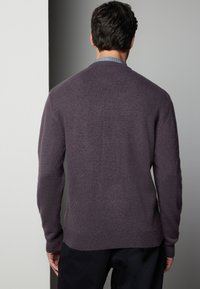 Pull en maille violet avec un col rond, tissu texturé, poignets et ourlet côtelés, et une silhouette ajustée, vu de l'arrière.