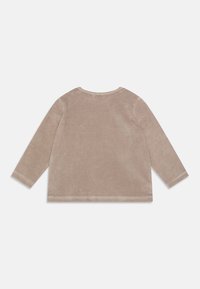 Długi rękaw, top w miękkim beżowym welurze, okrągły dekolt, gładka tekstura, bez wzorów i ozdób, przeszyty dół z minimalnymi detalami.