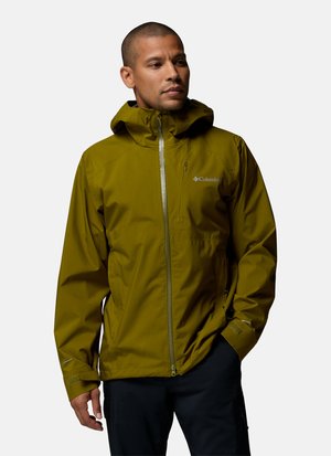 Mann trägt olivgrüne Columbia wasserdichte Jacke mit Kapuze und schwarze Hose, steht vor einfachem Hintergrund.