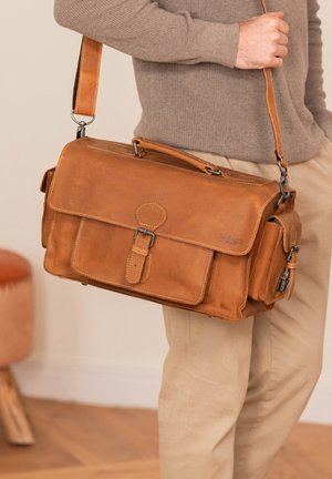 Braune Leder-Umhängetasche mit einem oberen Griff, verstellbarem Trageriemen, Klappe vorne und Seitentasche. Mit Nähte und einem Metallverschluss ausgestattet.