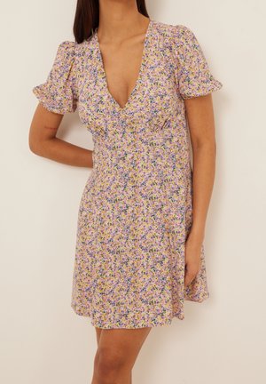 Bloemjurk met een diepe V-hals, korte puffmouwen en een lichtgewicht stof met een mix van paarse, gele en groene patronen.