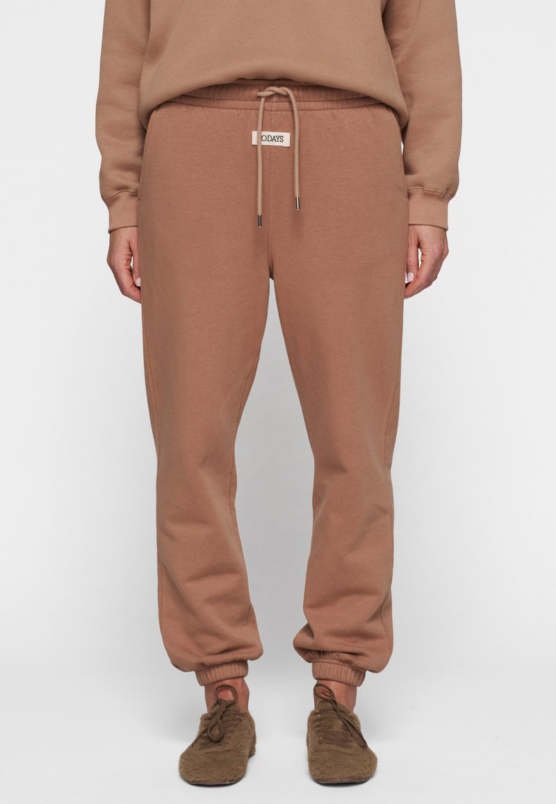 Brune bomulds sweatpants med elastiske manchetter, justerbar snor i taljen og et vævet mærke på forsiden. Blød tekstur, afslappet pasform.