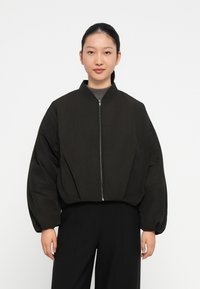 Zwarte cropped bomberjack met een ritssluiting, oversized mouwen en een hoge kraag. Het materiaal lijkt glad en heeft een lichte textuur.