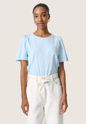Light blue short-sleeve top with a crew neck and gathered shoulder detail, paired with white textured, drawstring pants.