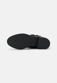 Suela de zapato negra con una superficie de goma texturizada, tacón rectangular y indicador de tamaño en relieve. No presenta patrones o acentos distintivos.