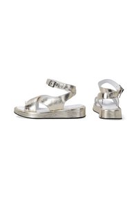 Metalické zlaté sandály s plochou, texturovanou podrážkou, otevřenou špičkou a nastavitelným páskem kolem kotníku. Disponují křížovým designem a perforovanou stélkou.