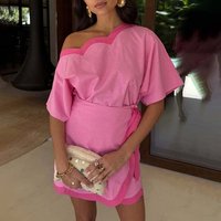 Rosa averkantet topp med en bølget kant, parret med et matchende innpakningsskjørt. Accessorert med en teksturert clutch og lagdelte smykker.