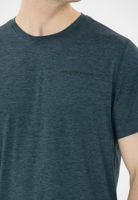 Mörkblå-grön tränings T-shirt i blandad tyg. Har rundad halsringning och en subtil svart "ENDURANCE" logotyp på bröstet.