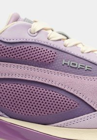 Zapatilla morada que presenta materiales de malla y ante, texturas suaves, un logo "HOFF" prominente y un diseño en capas con tonos contrastantes.