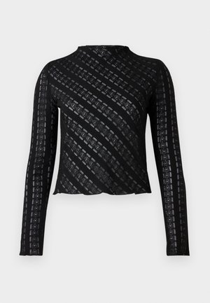 Schwarzes Langarmoberteil mit hohem Ausschnitt, das ein strukturiertes Muster aus schrägen Streifen und Ausschnittdetails aufweist. Gekürztes Design.