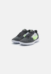 Scarpe sportive di colore grigio scuro con accenti verdi. Presentano una combinazione di suede testurizzato e mesh nella parte superiore, suola leggera e design con lacci.