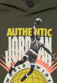 Φούτερ με κουκούλα σε ελιά πράσινο χρώμα με γραφικό ενός παίκτη μπάσκετ εν δράσει. Το κείμενο γράφει "AUTHENTIC JORDAN WORLDWIDE" με έντονα χρώματα και φθαρμένη υφή.