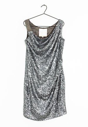 Ärmelloses Cocktailkleid aus silbernen Pailletten mit einer perlenbesetzten linken Schulterträger, drapiertem Ausschnitt, hängt an einem schwarzen Kleiderbügel vor weißem Hintergrund.