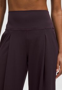 Mauve korkeavyötäröiset housut, joissa on pleated-muotoilu ja sileä, joustava kangas. Ominaisuuksiin kuuluu leveä vyötärö ja kontrastivärinen ompelu.