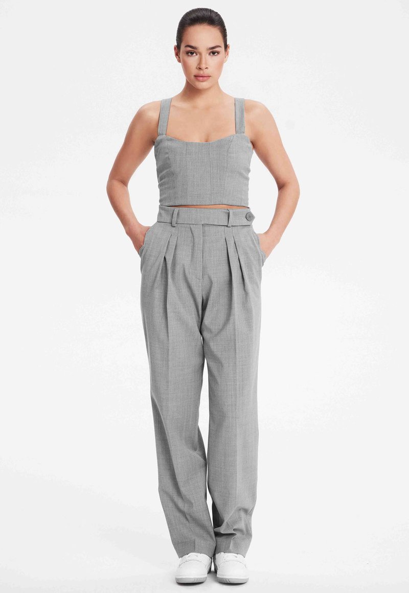 Grijze getailleerde crop top met brede bandjes, gecombineerd met hooggesneden grijze plooibroek. Beide kledingstukken hebben een gladde textuur en een nauwkeurige afwerking.