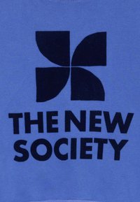 Zila auduma, kurā ir liels tumši zils grafisks attēls ar četru daļu ziedu formu virs teksta "JAUNĀ SABIEDRĪBA" biezā, tumšā fontā.