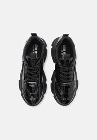 Sorte patentlæder sneakers med kraftig sål, teksturerede paneler og kontrasterende snørebånd; har branding på indersålerne.