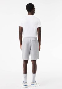 Gray cotton shorts with an elastic waistband and side pockets, paired with a white t-shirt and gray socks, viewed from the back.