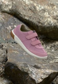 Lyserød ruskinds sneaker med to justerbare Velcro-stropper, rund tå, hvid gummisål og teksturerede sideakcenter.