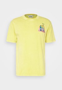 Camiseta de algodón amarilla con cuello redondo, mangas cortas y un diseño bordado de palmeras y botellas en el lado izquierdo del pecho.